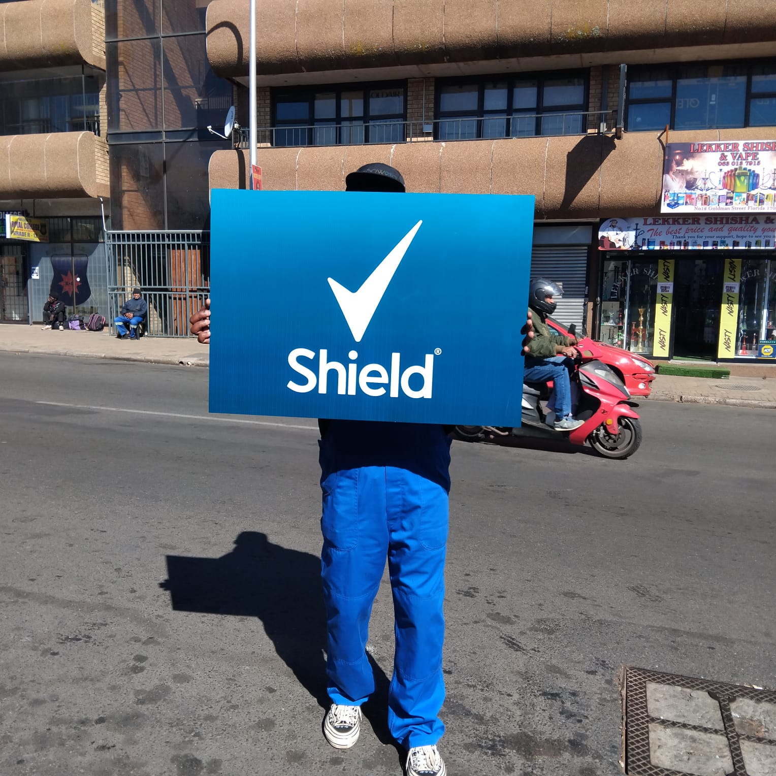 Shield branded activation board held on a street